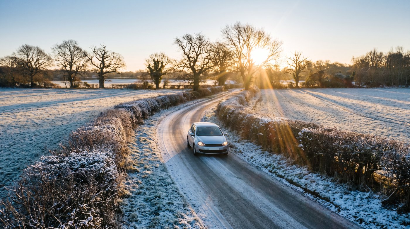 A car on a frosty country lane in low winter sun